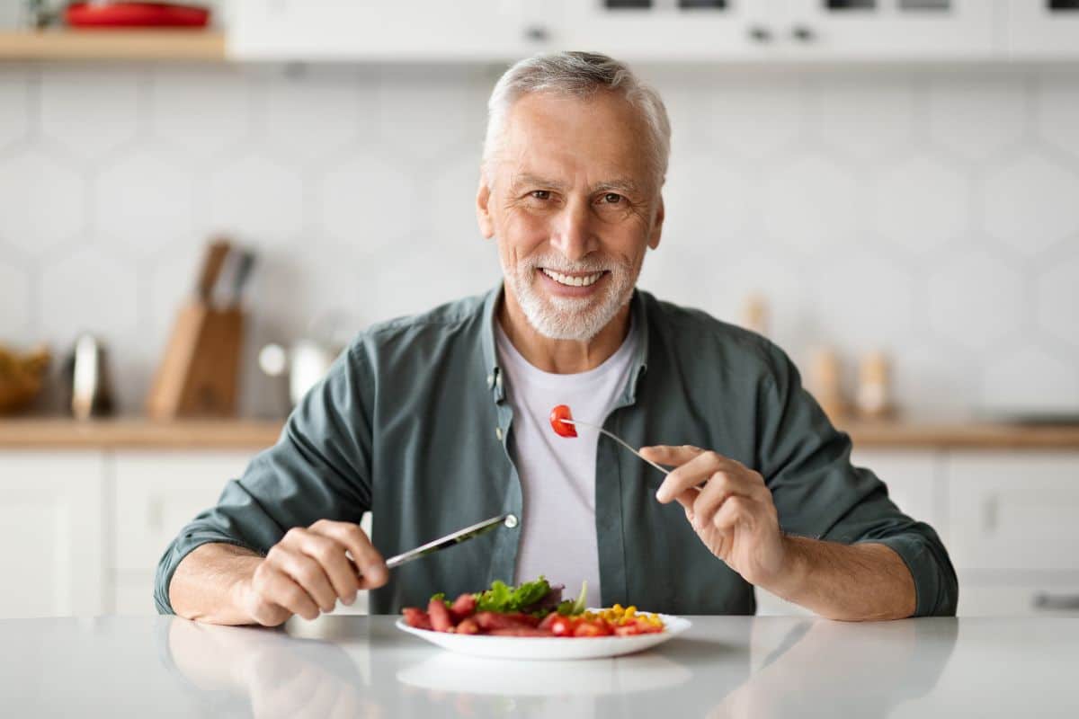 Patient enjoying a healthy meal with improved chewing ability from implant overdentures in Lubbock, TX