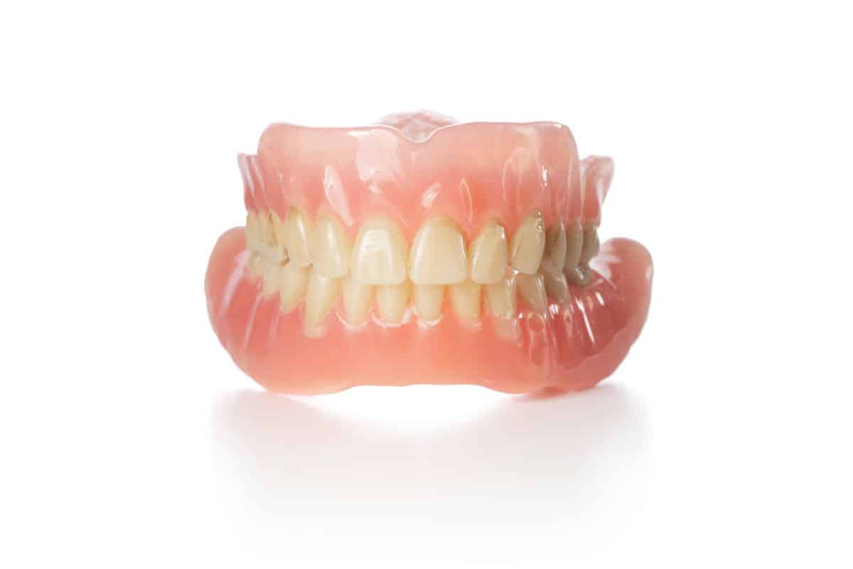 A full set of dentures is displayed, showing a removable solution for replacing missing teeth.