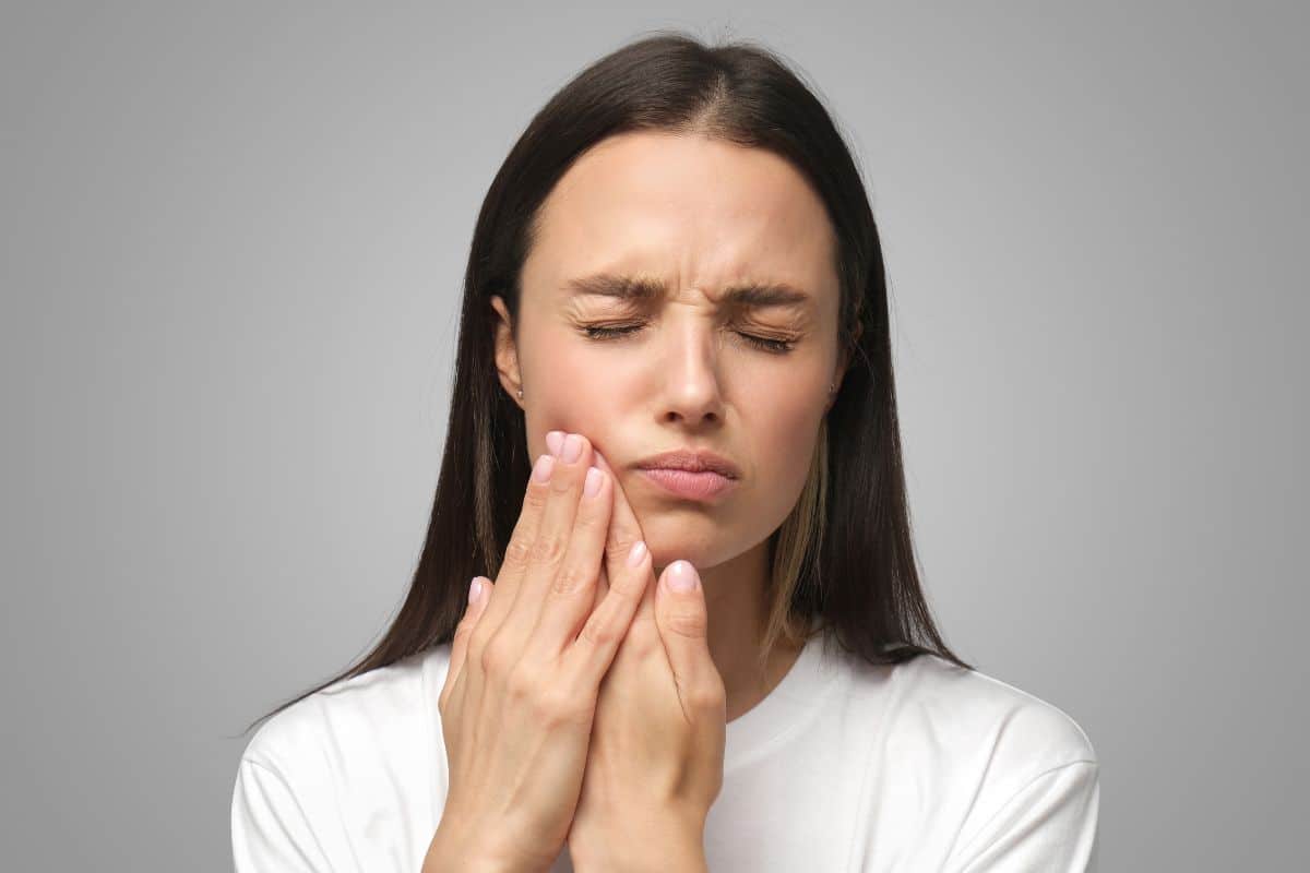 Woman experiencing gum pain while learning about laser gum disease treatment and traditional surgery